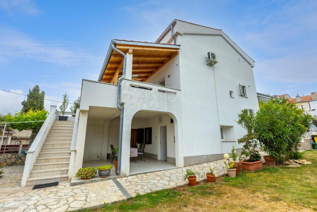 a white house with a porch and stairs at Apartment Anton in Punat