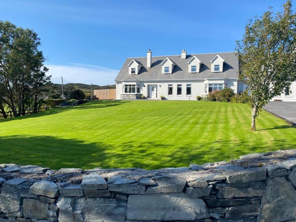a large white house with a stone wall at Racecourse Lodge Apartment in Clifden