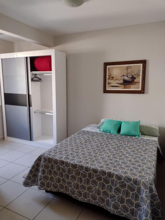 Schlafzimmer mit einem Bett und einer Tür zu einem Kühlschrank in der Unterkunft Kitnet top 04 Prox do centro e da UEM in Maringá
