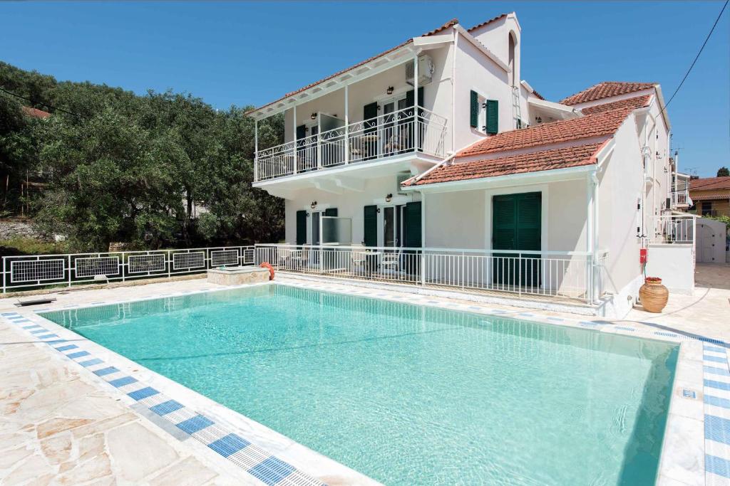 a large swimming pool in front of a house at Marika Apartments in Kassiopi