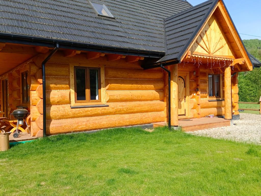 a log cabin with a black roof at Chata Dziewięćsił in Tylmanowa