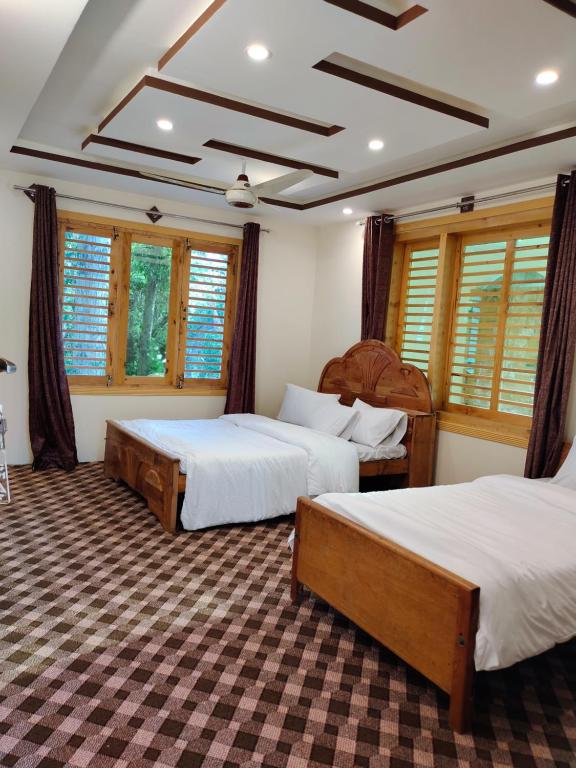 a bedroom with two beds and windows and a coffered ceiling at PYRAMID LODGE in Skardu