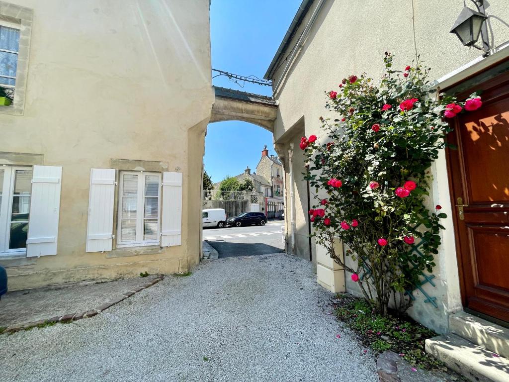 an entrance to a building with a bush of roses at Le Cosy in Bayeux