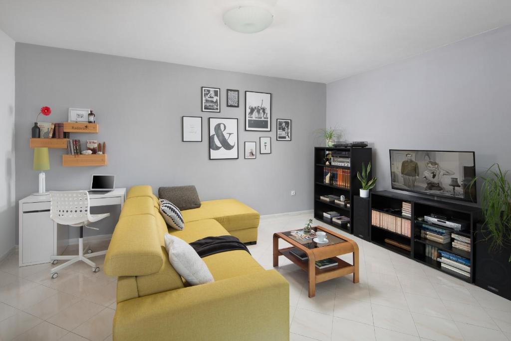 uma sala de estar com um sofá amarelo e uma mesa em Ana Apartment em Rabac