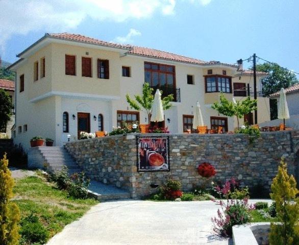 a large white house with a stone wall at Guesthouse Kolenti in Portaria