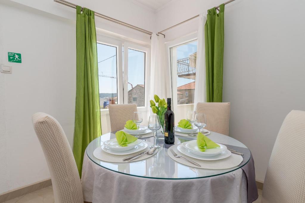 comedor con mesa y cortinas verdes en Apartment Roko, en Trogir