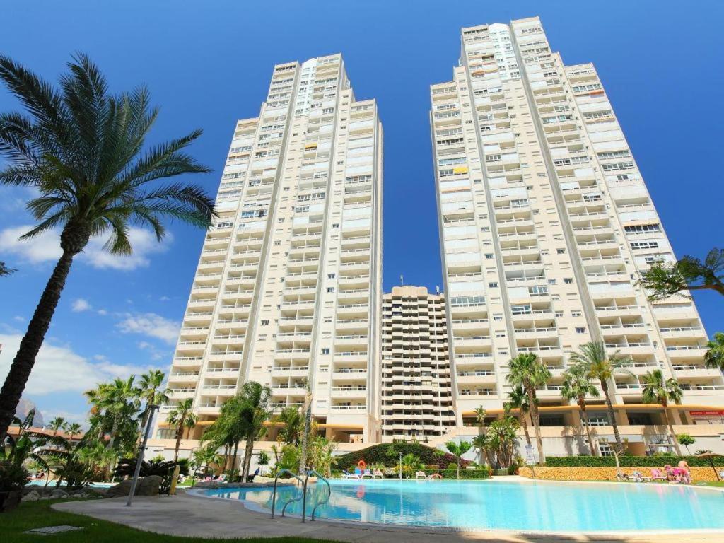 twee hoge witte gebouwen met een zwembad en palmbomen bij Gemelos 22-Fincas Benidorm in Benidorm