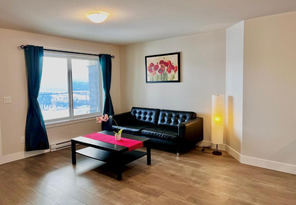 a living room with a black leather couch and a table at Kelowna new lake view 2bedrooms suite close BIG WHITE in Kelowna