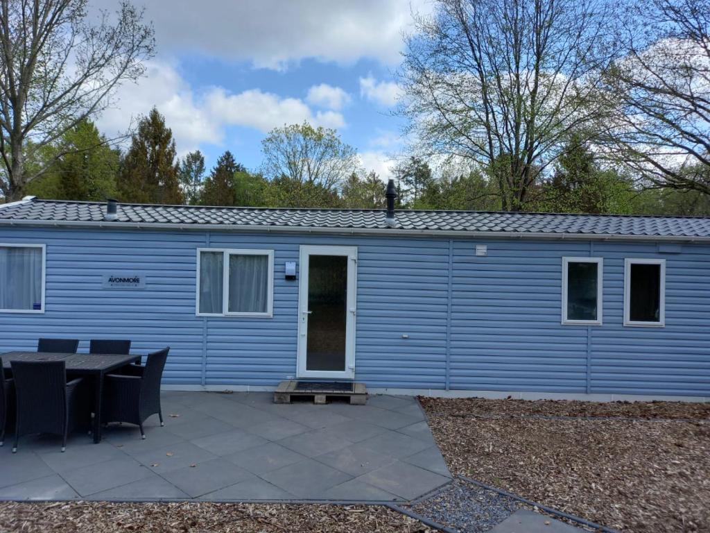 een blauw gebouw met een tafel ervoor bij Veluwe Chalet Epe in Epe