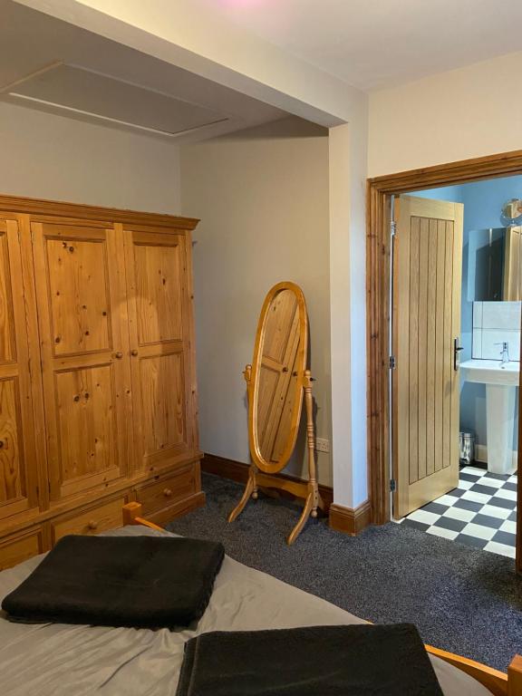 a bedroom with a bed and a wooden wardrobe and a mirror at Masons Nook 292 Mansfield Road NG174HR in Skegby