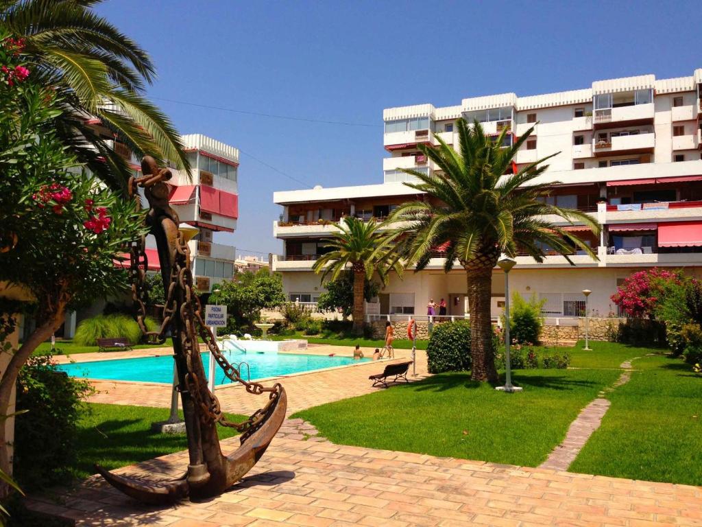 a resort with a hammock and a pool and a building at La Voreta in Villajoyosa