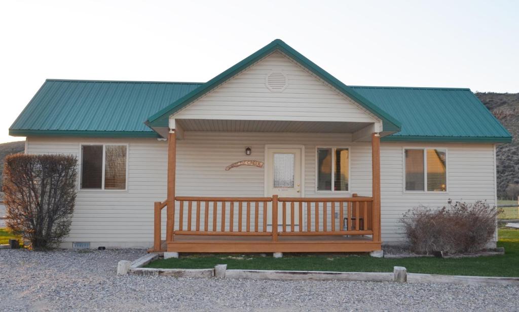 une petite maison blanche avec un toit vert dans l'établissement Sleepy J Cabins, à Swan Valley