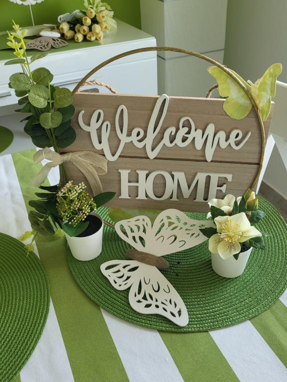 a welcome home sign on a table with plants at Apartment Ksenija in Crikvenica
