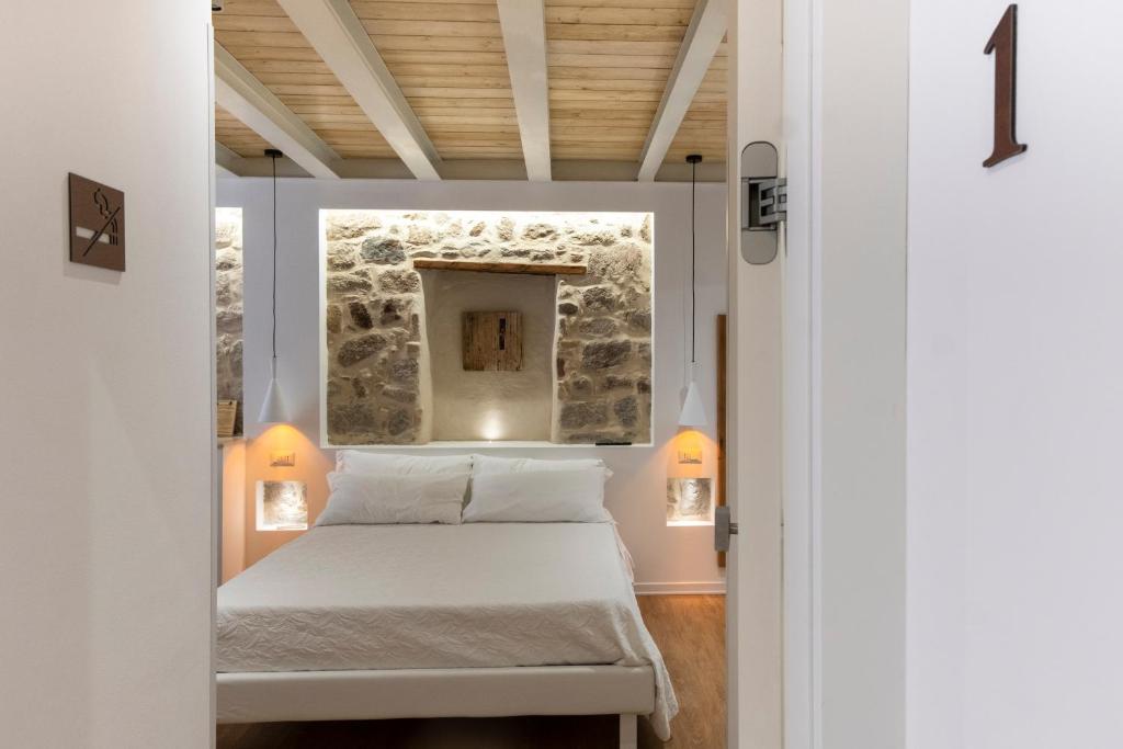a bedroom with a bed and a stone wall at In centro da Viola - Eco Design Rooms in Olbia