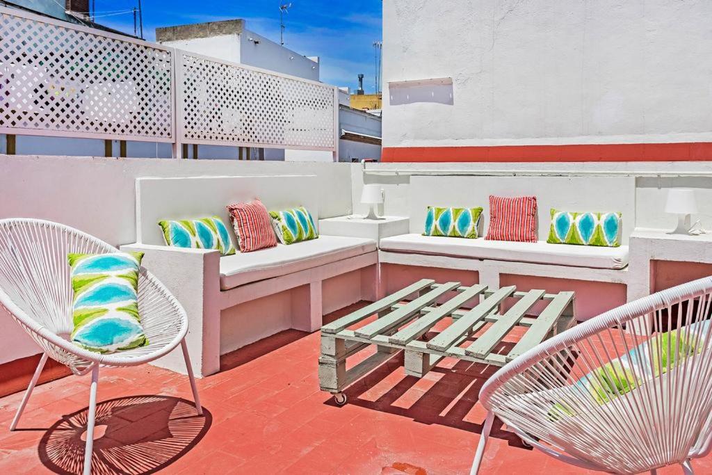 einen Balkon mit Stühlen und einer Bank auf einem Gebäude in der Unterkunft FAM Sevillian Townhouse in Sevilla