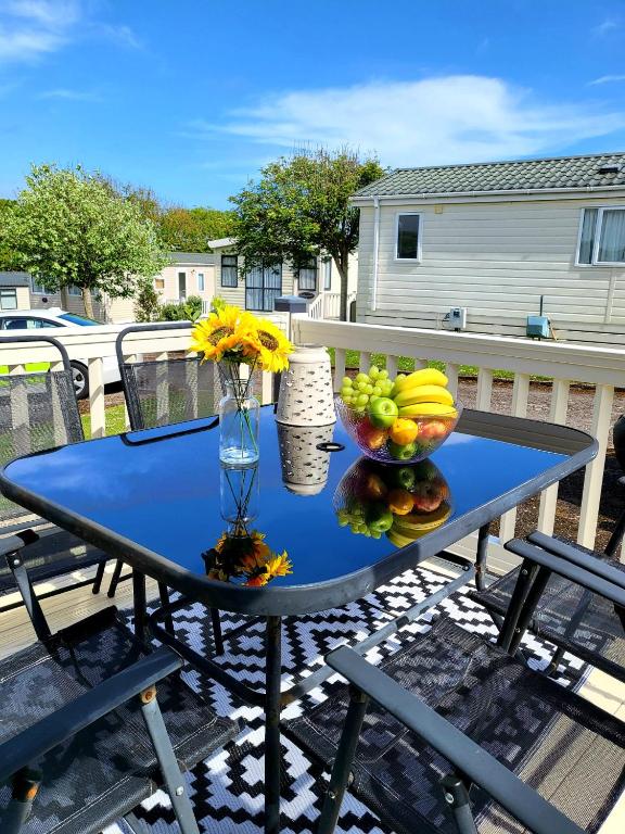 a blue table with a bowl of fruit on a patio at Luxury Seaside Retreat Holiday Home - Shorefield Country Park in Downton
