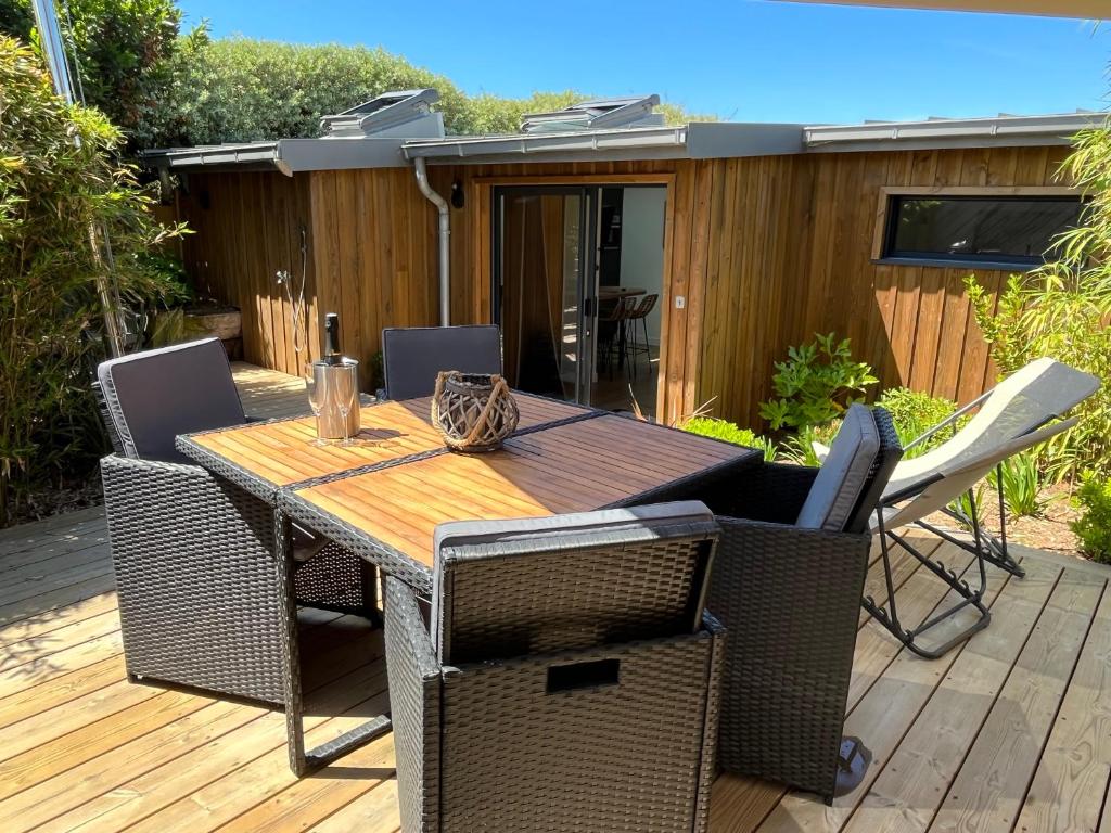 a wooden table and chairs on a deck at Lodge LE CABANON accès direct plage ! in La Turballe