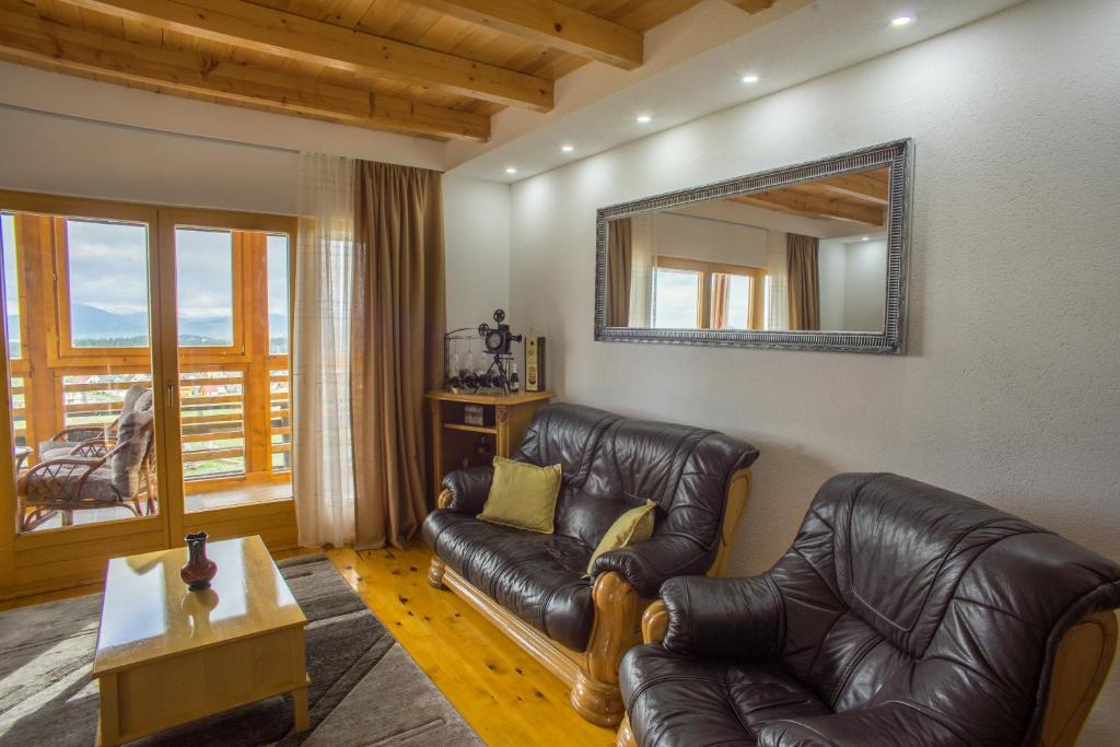 a living room with a leather couch and a mirror at Mountain House AMI in Žabljak