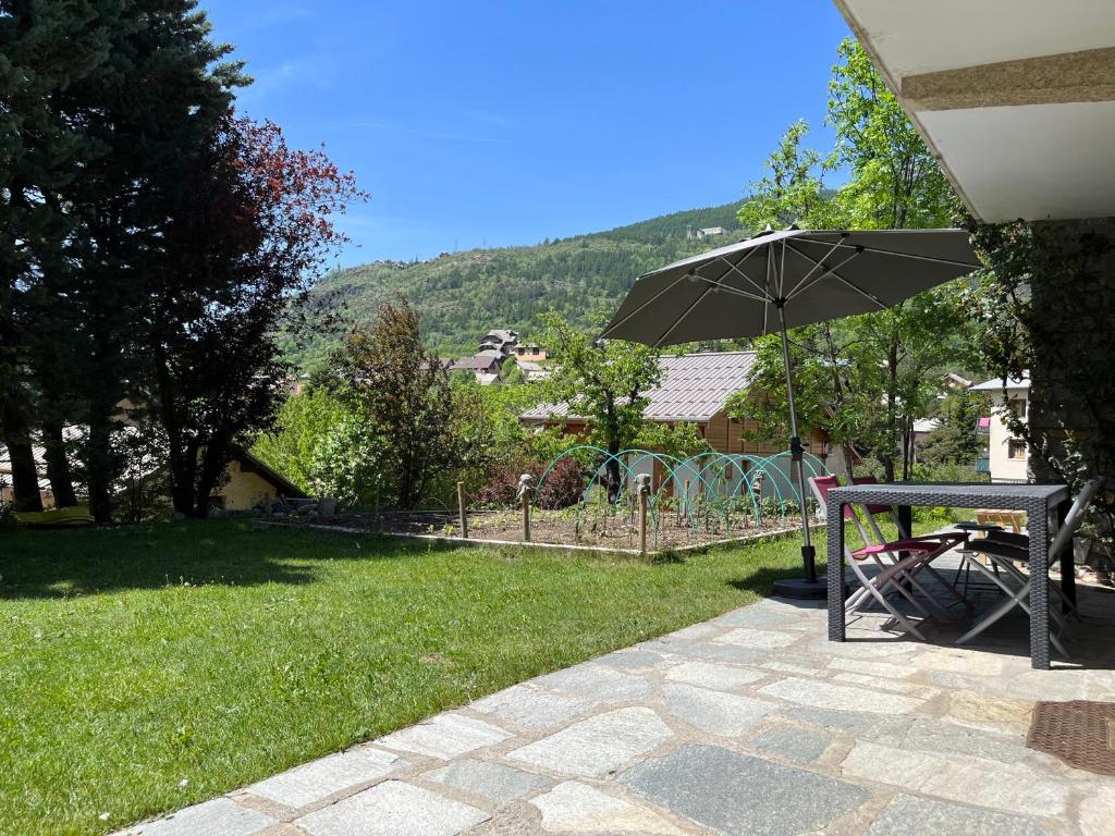 a table and an umbrella in a yard at Appartement rez de jardin, 2 chambres/ 4 personnes, garage. in Briançon