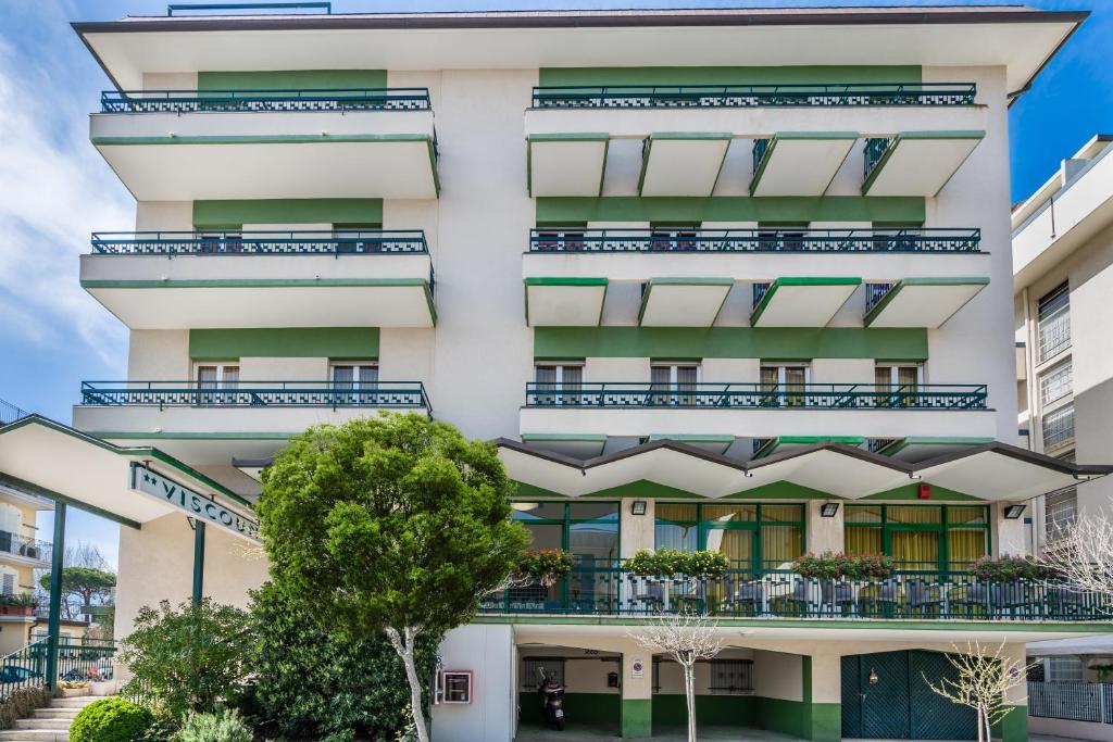 um edifício de apartamentos com varandas e árvores em Hotel Viscount em Riccione