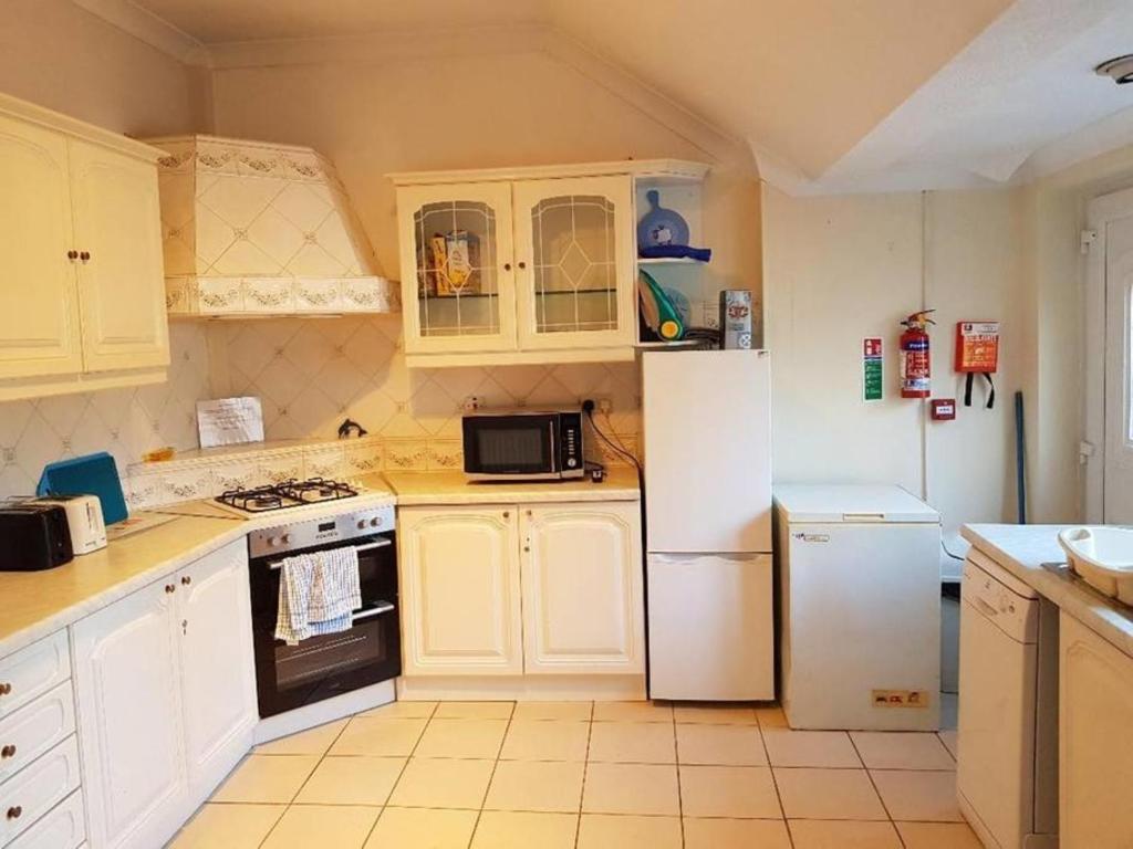 a kitchen with white cabinets and a white refrigerator at The Hebburn Great House in Hebburn-on-Tyne