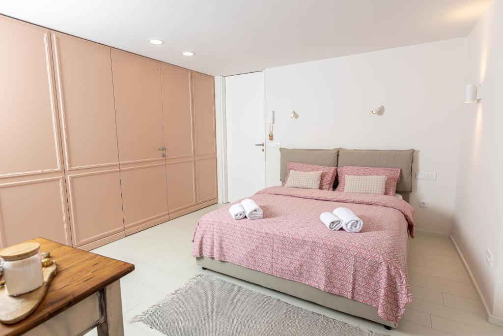 sypialnia z różowym łóżkiem i 2 ręcznikami w obiekcie Piran Holiday Apartments in the city center w mieście Piran