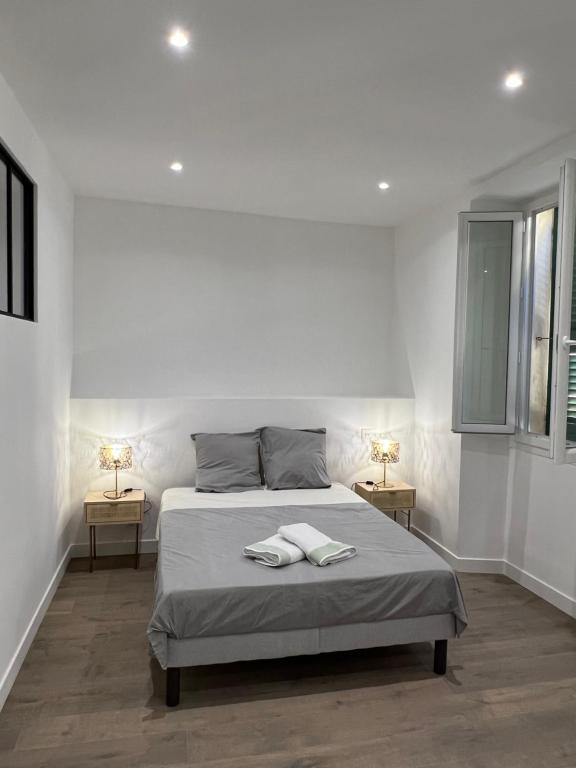 a white bedroom with a bed with two tables at Appartement T2 vieille ville d’Ajaccio in Ajaccio