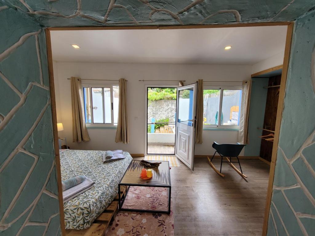 a room with a bed and a table and windows at The Handmade House Azores in Porto Formoso