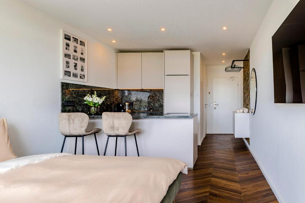 a kitchen with white cabinets and two chairs in a room at Apartment im Olympia Hotel Schilksee in Kiel