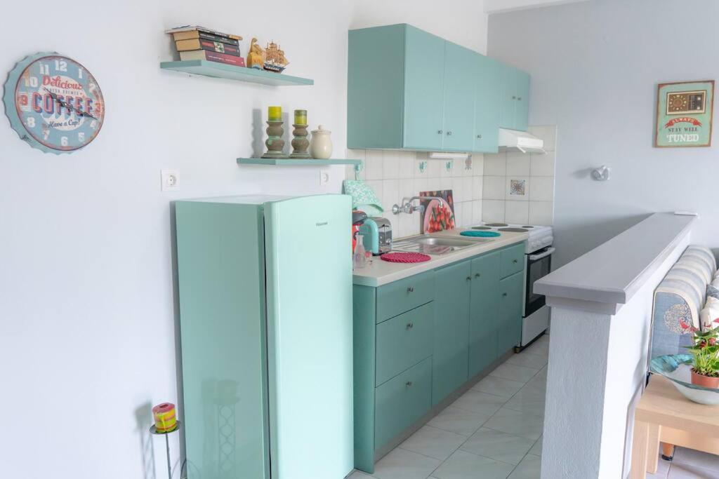 La cuisine est équipée de placards bleus et d'un réfrigérateur. dans l'établissement Renovated apartment in Adelianos Kampos, à Adelianos Kampos