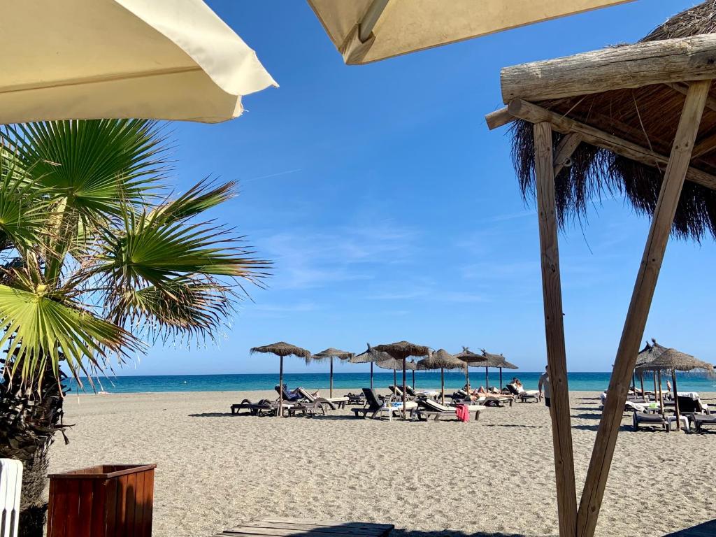 a beach with chairs and umbrellas and the ocean at La Duquesra Serviced Apartments in Málaga