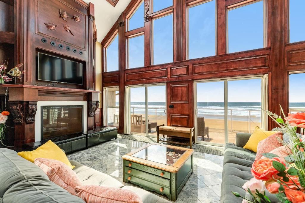 a living room with a couch and a fireplace and the ocean at Oceanfront Seascape in Rockaway Beach