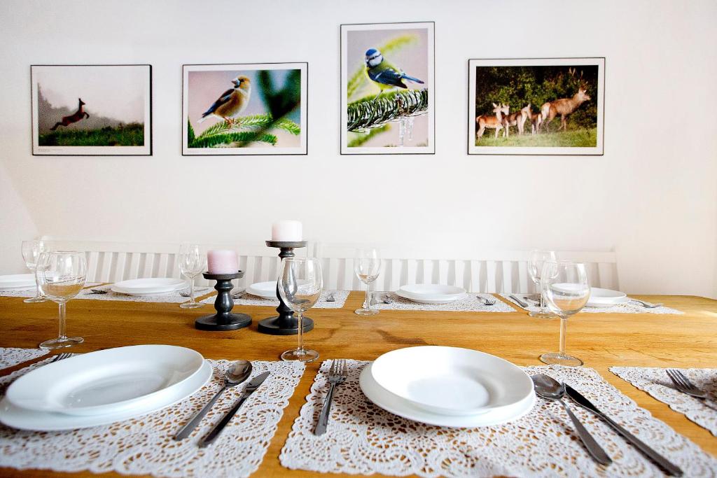 a dining room table with plates and glasses and pictures on the wall at Miętowa Dolina in Baligród