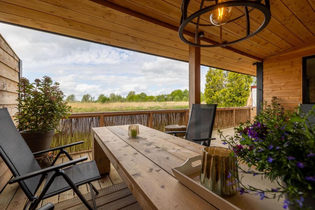 una terrazza in legno con tavolo e sedie in legno di Buiten Huisje aan de Vaart 2 a Matsloot