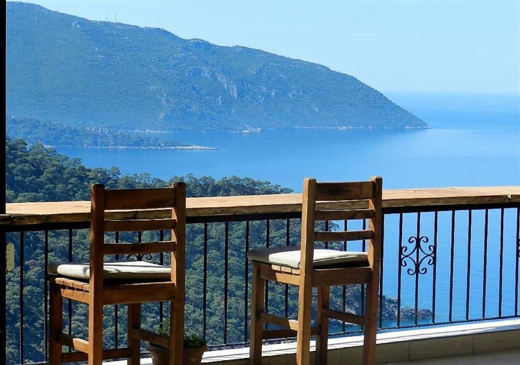 Duas cadeiras numa varanda com vista para a água em Kabak Misafir Evi em Muğla