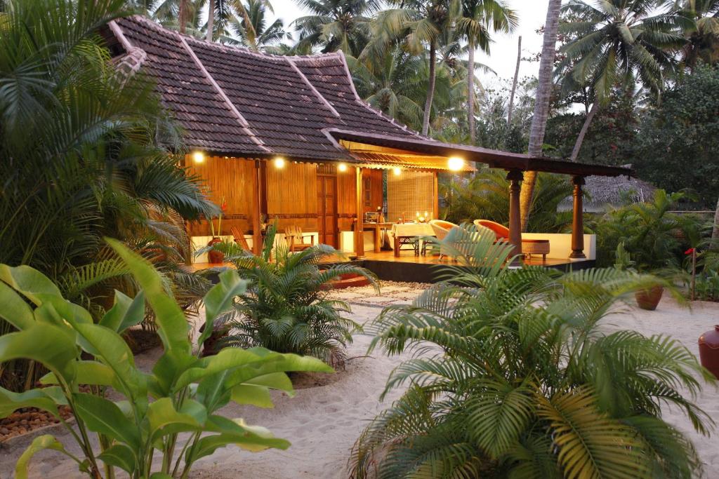 Ein Resort mit einem Holzgebäude mit Tischen und Stühlen in der Unterkunft Amritara A Beach Symphony in Mararikulam