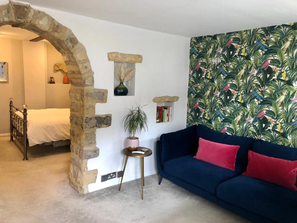 a living room with a blue couch and a bed at The Old Studio in Knaresborough