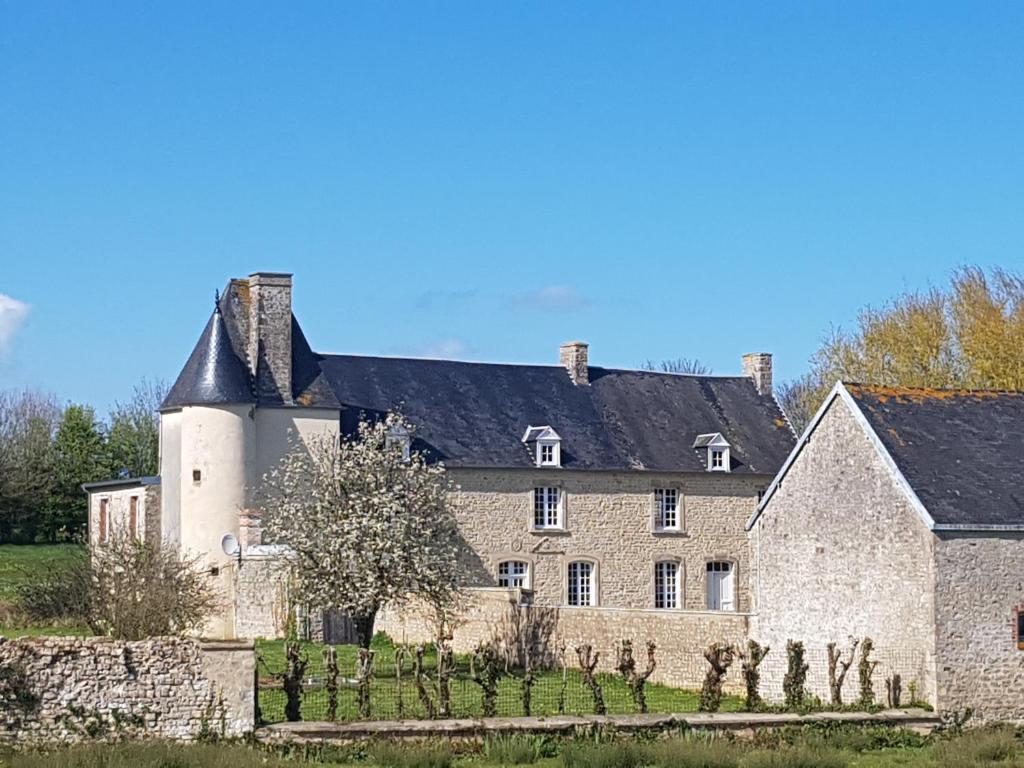 un grand bâtiment en pierre avec un toit noir dans l'établissement Manoir de Pierreville, à Audouville-la-Hubert