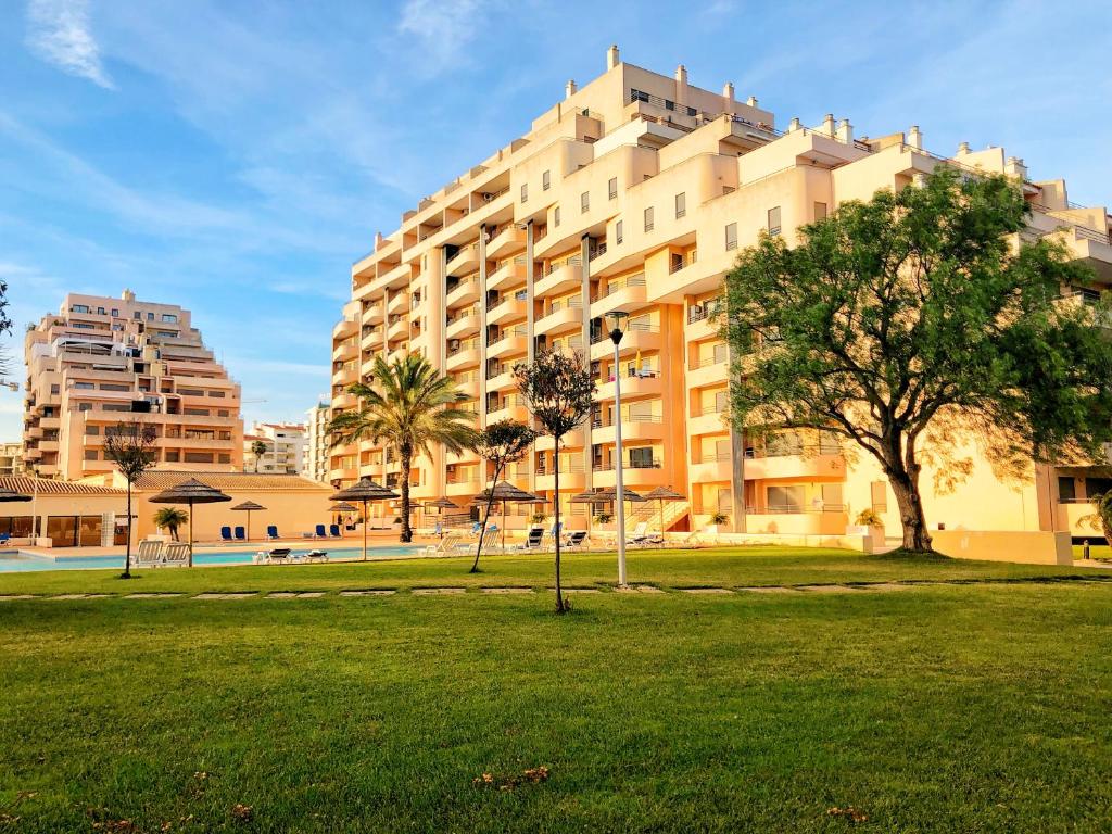 un grande edificio con un parco di fronte ad esso di Beautiful Apartment in paradisiac Praia da Rocha a Portimão