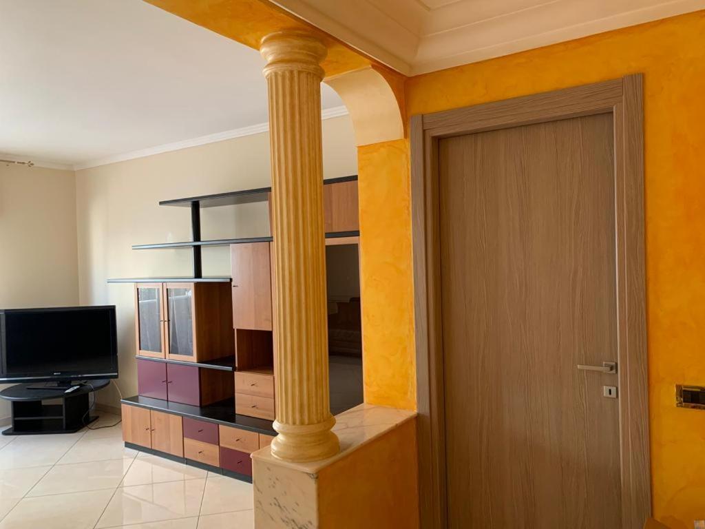 um quarto com uma coluna, uma televisão e uma porta em Soffio di Sicilia em Érice