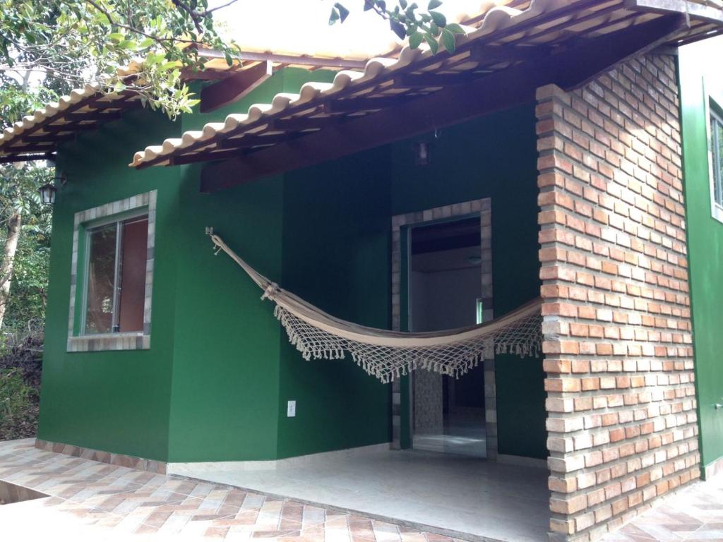 ein grünes Haus mit einer Hängematte draußen in der Unterkunft Chalé Verde - Vale do Capão in Vale do Capao