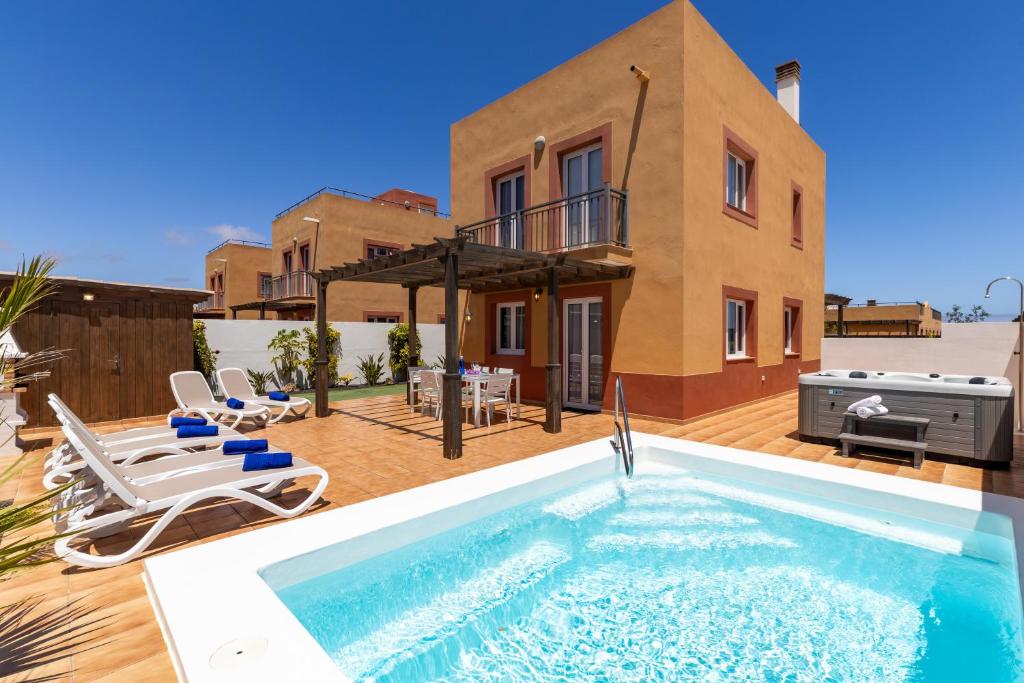 a villa with a swimming pool in front of a house at Villa Leonor - Mirador de las Dunas in Corralejo