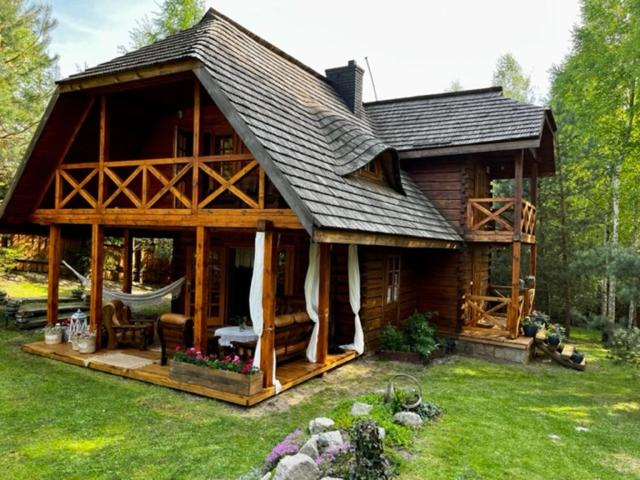 a large wooden cabin with a hammock in the yard at Myszówka 