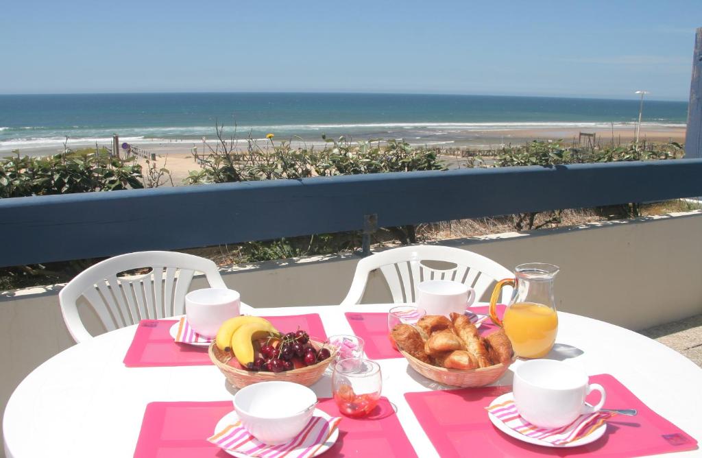 una mesa con dos cestas de comida y una playa en Résidence Néméa Les Gourbets, en Mimizan-Plage