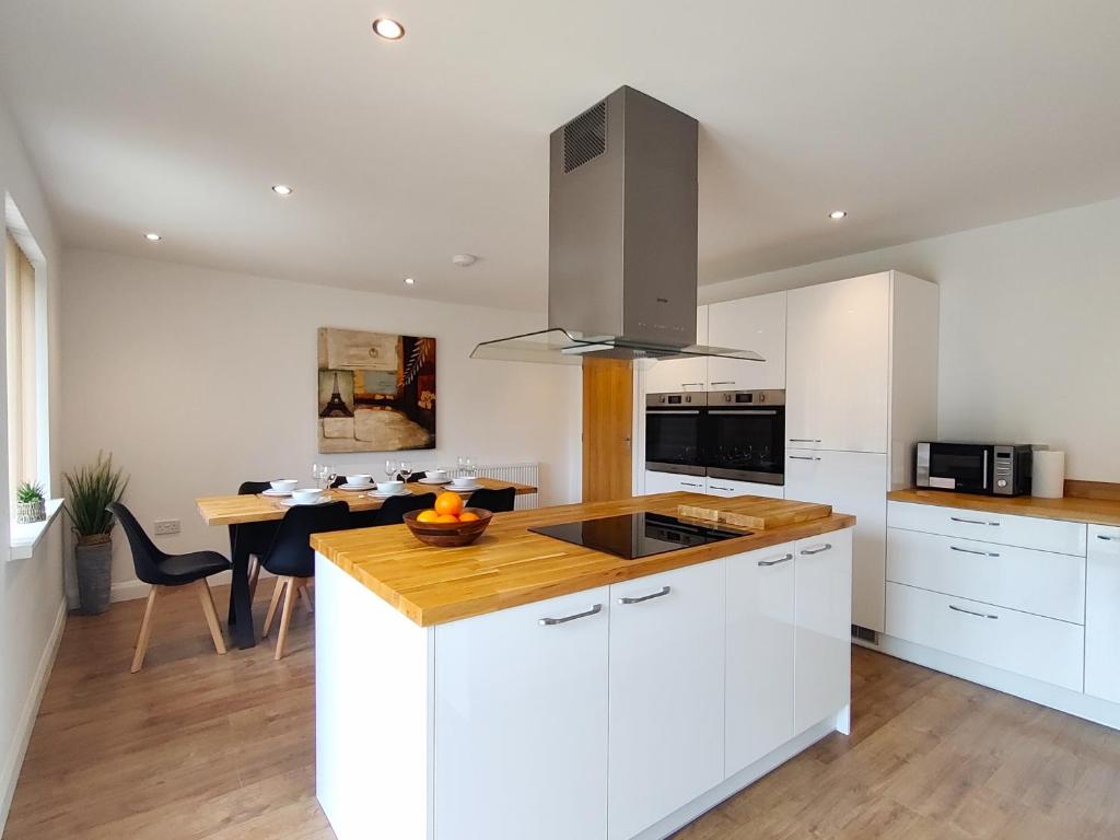 a kitchen with white cabinets and a wooden counter top at Orchard View - 4-Bed Home In Kempsford, Cotswolds 
