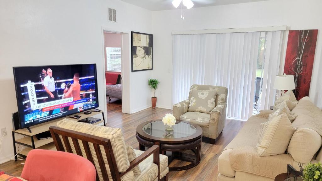 a living room with a large tv and a couch and chairs at 2 Master Suite Apartment near North Florida Regional Med, UF Health, & Mall in Gainesville