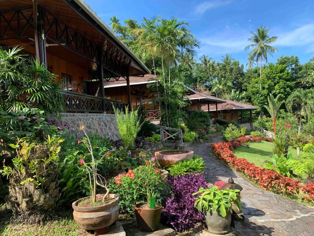 Lumbalumba Resort - Manado في مانادو: حديقة امام بيت به نباتات