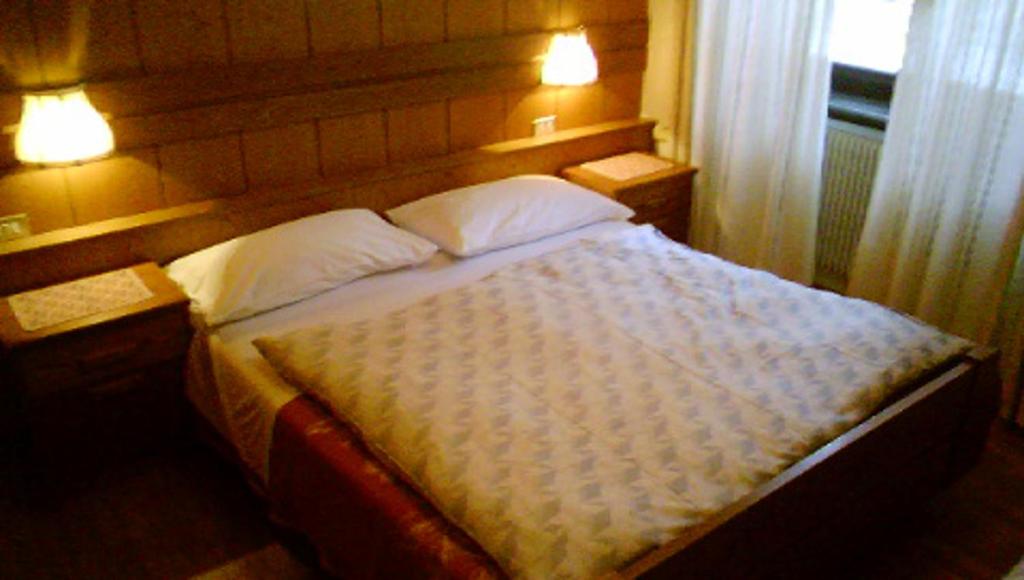 a bedroom with a bed with two pillows and a window at Campiglio Bilocale Monte Spinale in Madonna di Campiglio