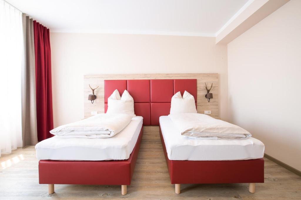 two beds in a room with red and white at Aparthotel Altomünster - Garni in Altomünster