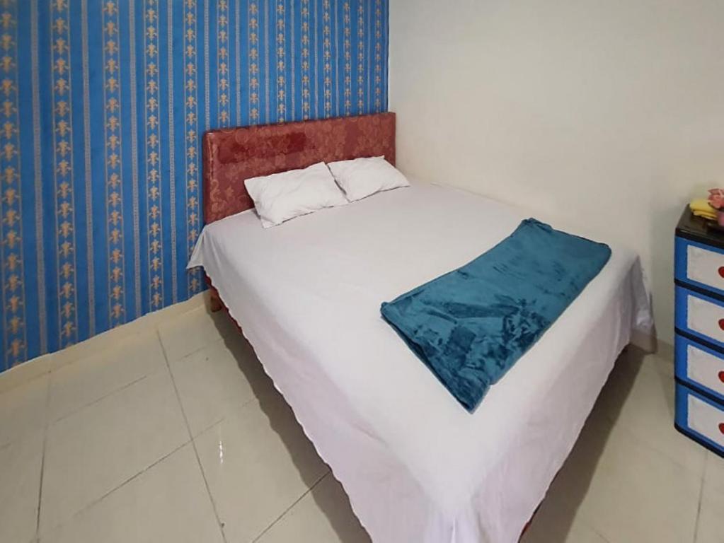 a bedroom with a white bed with a blue wall at RedDoorz Syariah at Labuhan Maringgai Lampung in Mataram-baru